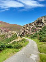 Panoramic view of North Wales countryside with lush green hills and rugged cliffs, showcasing the scenic beauty of the region